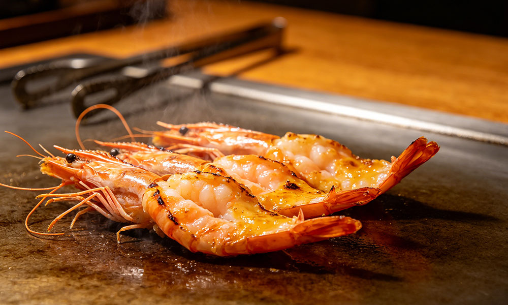 Grilled butterflied shrimp on teppanyaki griddle, sizzling with steam