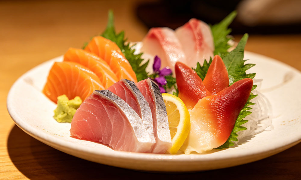 Assorted sashimi platter with salmon, tuna, surf clam, wasabi, and lemon