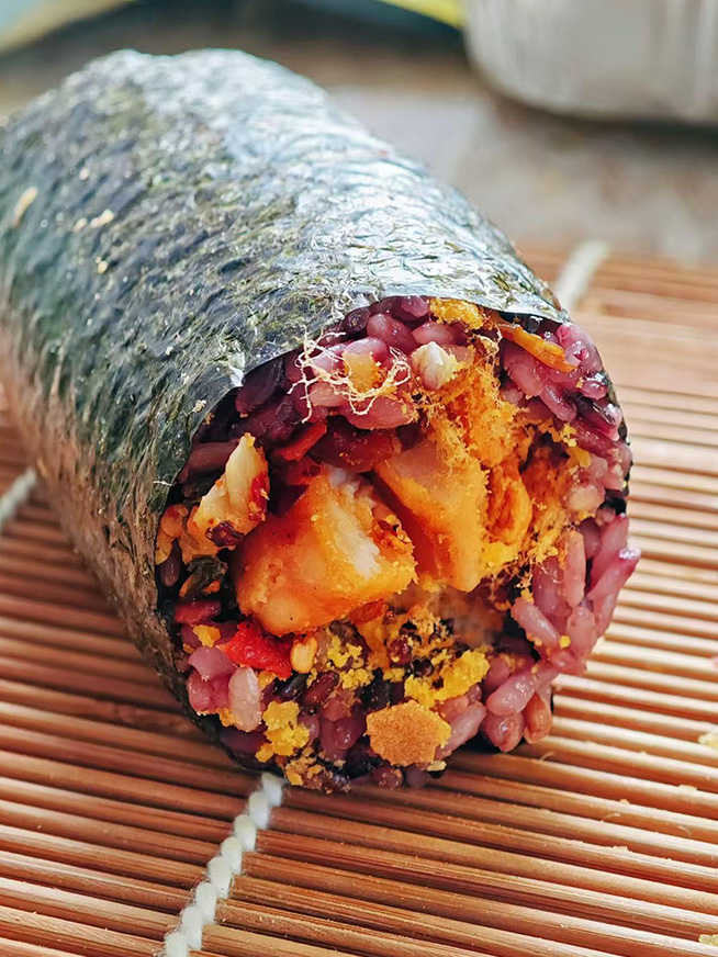 Nori-wrapped black rice roll stuffed with fried fish, flaky pork floss and savory pickled veggies at Meet Again Cafe, a Cafe in Scotch Plains