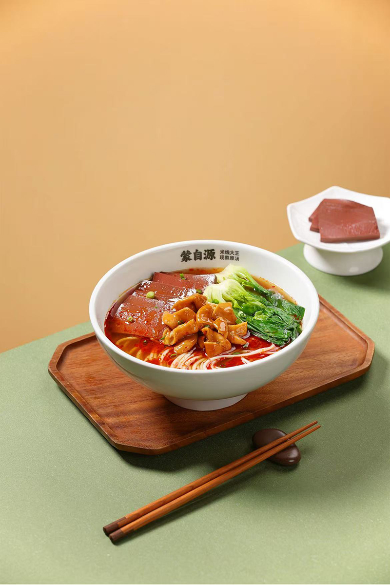 A bowl of Mengziyuan rice noodles in a red broth with pork intestines, blood curd, and greens at Meet Rice Noodle，a Authentic Rice Noodle Restaurant in Fremont