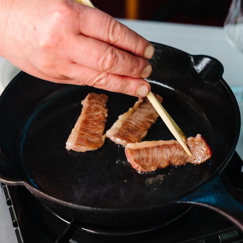 Cooking premium beef slices in a black pan at Megu French Japanese Cuisine in Fort Worth