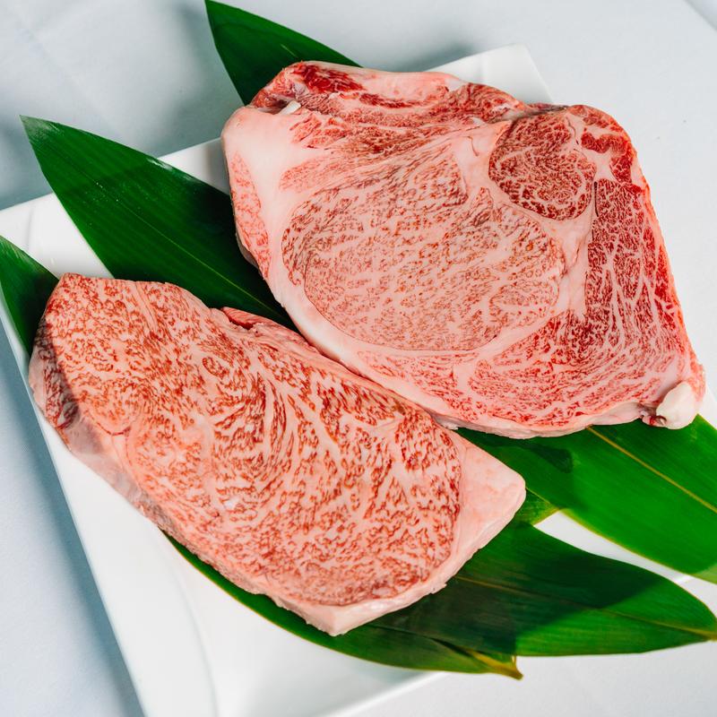 Two pieces of marbled Wagyu steak on green leaves at Megu French Japanese Cuisine in Fort Worth