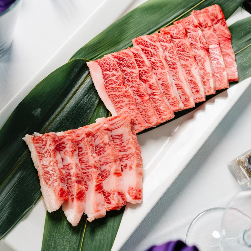 Premium thinly sliced beef on a white plate at Megu French Japanese Cuisine in Fort Worth