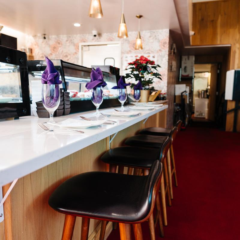 Sushi bar with purple napkins and golden lights at Megu French Japanese Cuisine in Fort Worth