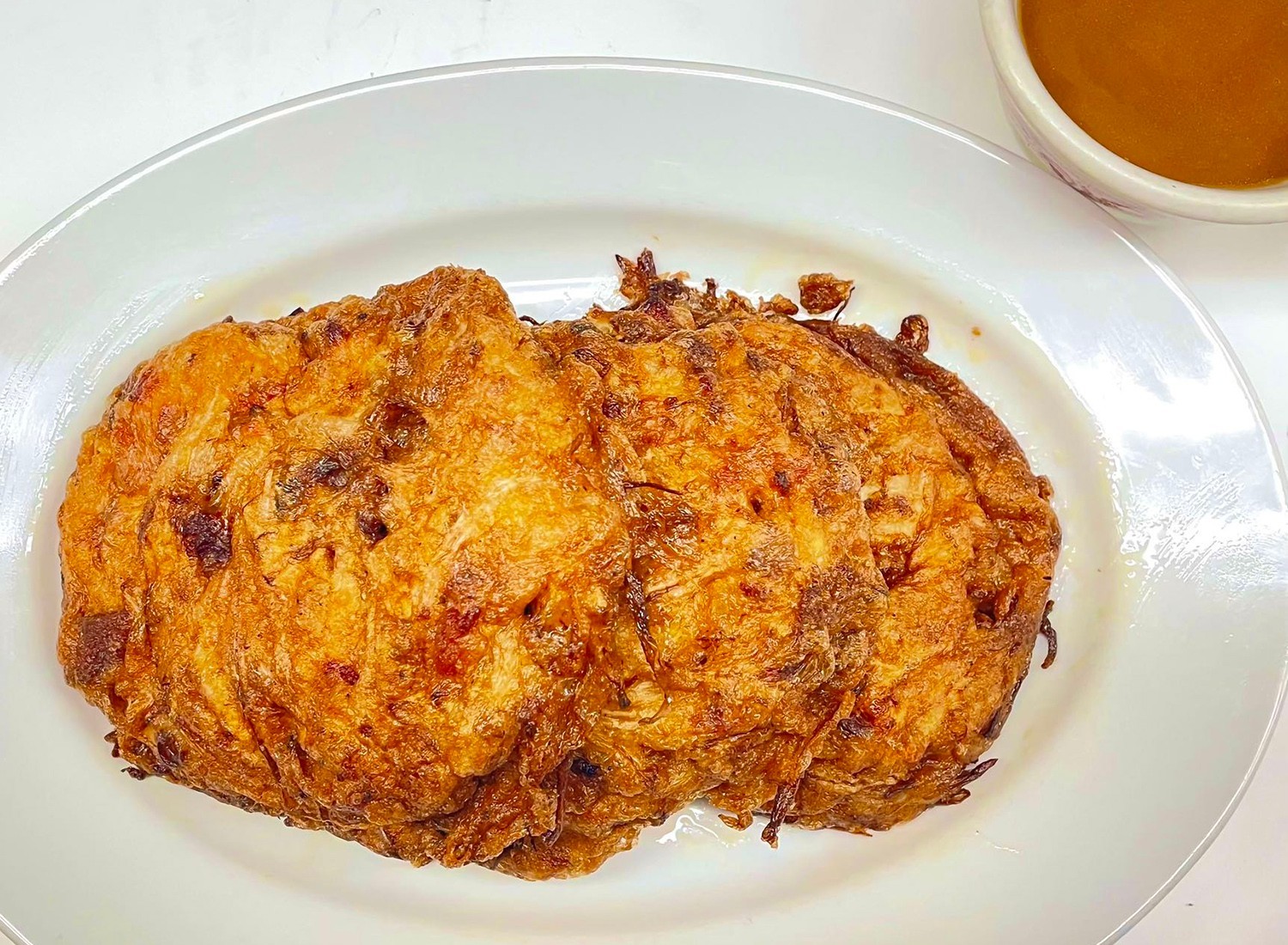 Fluffy omelette with savory fillings, served with a side of sauce at Mei-King Restaurant, a Chinese Restaurant in Pawtucket