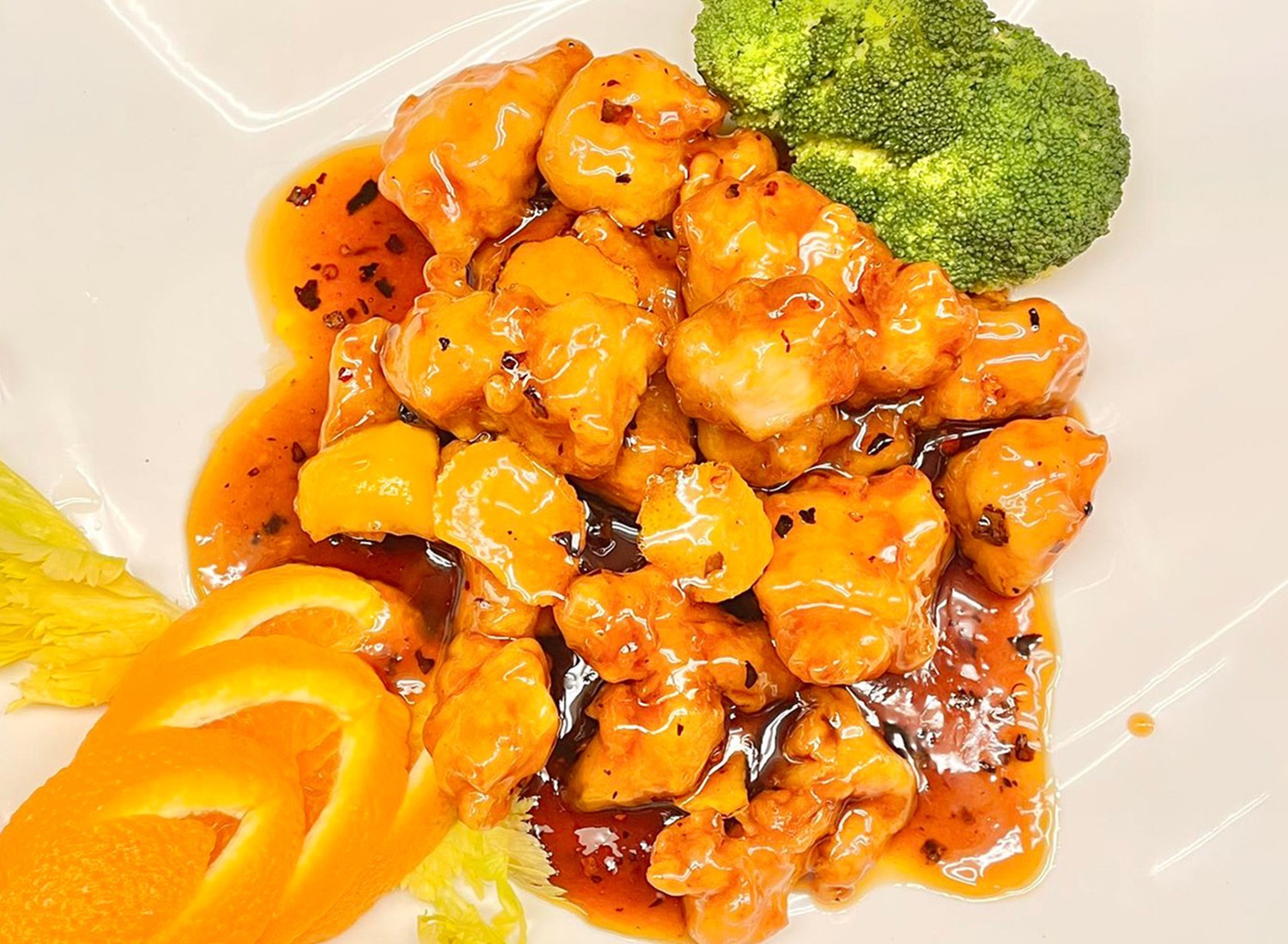 Tangy orange chicken with vibrant sauce, garnished with orange slices and broccoli at Mei-King Restaurant, a Chinese Restaurant in Pawtucket
