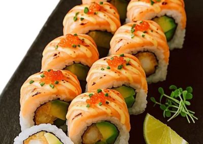 Salmon avocado sushi roll with creamy sauce, tobiko and lime wedge garnish at Mex Sushi Taco, a Asian restaurant in Place maspeth