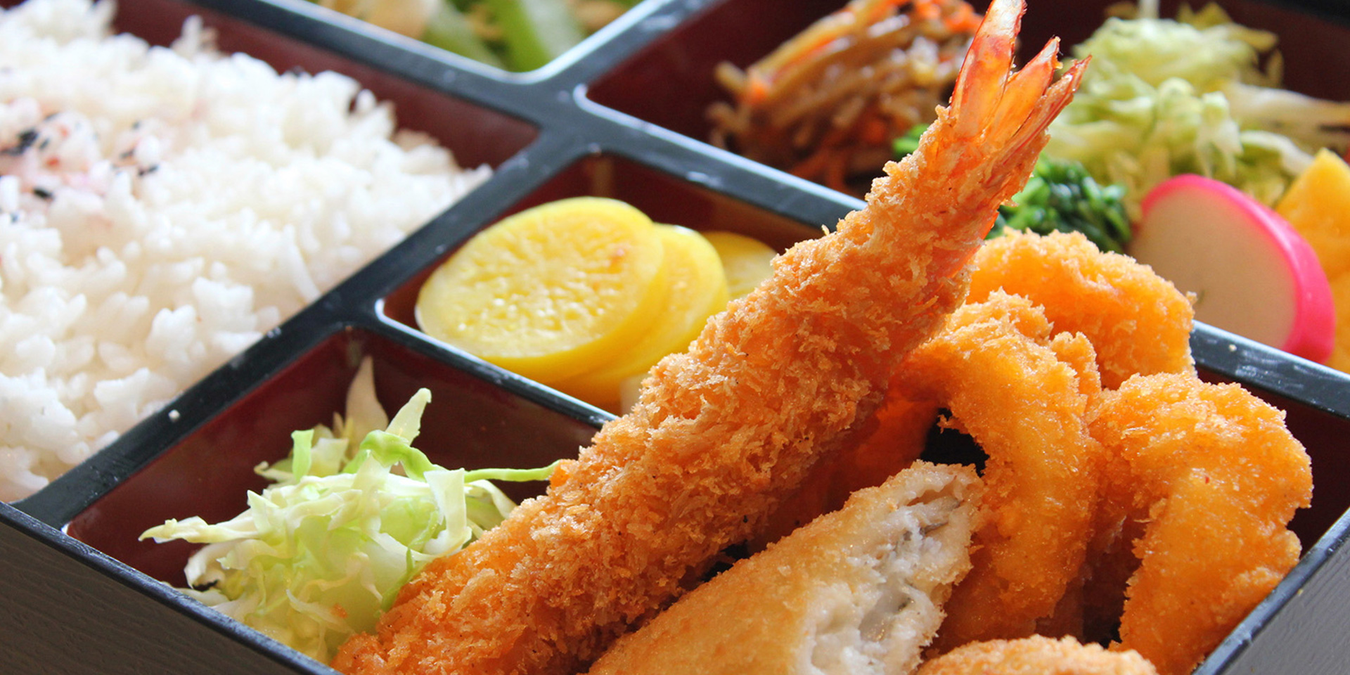 Japanese bento box with tempura shrimp, fried sides, rice, and assorted pickled vegetables at Mex Sushi Taco, a Asian restaurant in Place maspeth