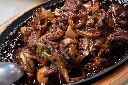Mint-Bistro-Asian-Fusion-Restaurant-Sizzling-Beef-Milford Sizzling plate of beef, cooked in a savory sauce at Mint Bistro,a Asian Fusion Restaurant in Milford