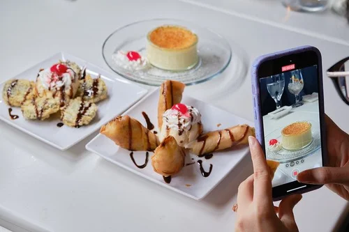 Desserts on a table with a person taking a photo of them using a phone at Mint Bistro，a Asian Fusion Restaurant in Milford