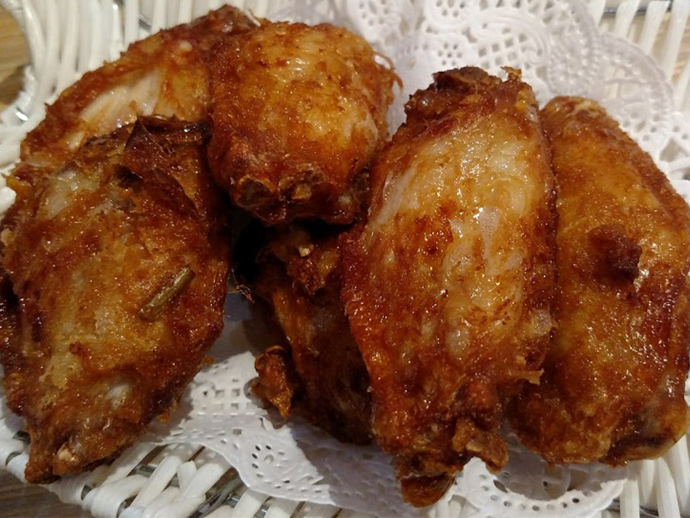 Crispy golden deep-fried chicken wings in woven basket at Mr Dumpling, a Chinese Noodle Restaurant in Rancho Cucamonga