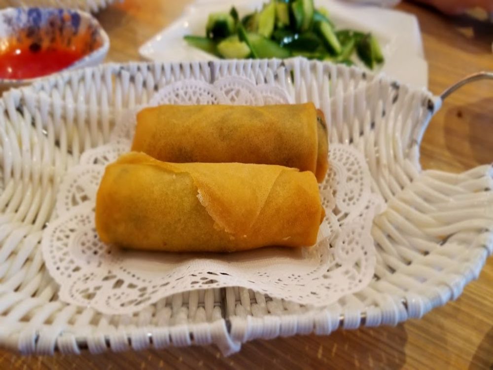 Two golden crispy fried vegetable spring rolls on lace paper at Mr Dumpling, a Chinese Noodle Restaurant in Rancho Cucamonga