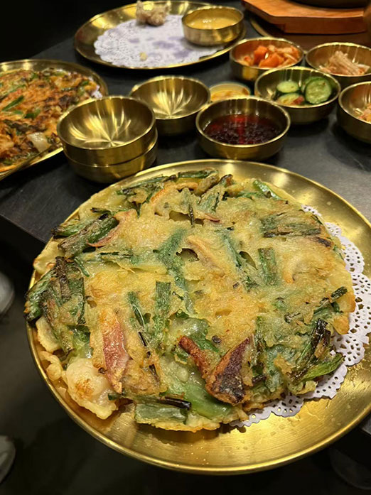 Savory seafood pancake with green onions and shrimp on a golden plate at Mr.Kimchi Korean Bistro, a Korean Restaurant in Oklahoma City