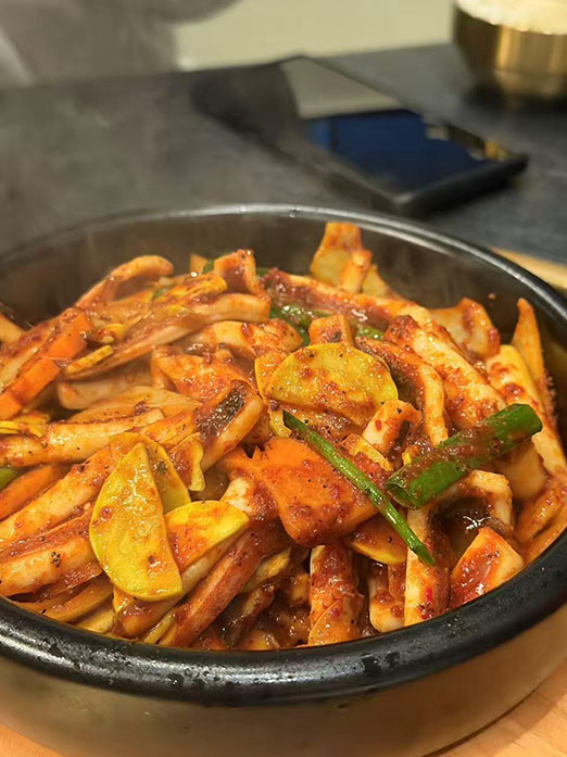Spicy stir-fried squid with vegetables in a stone bowl at Mr.Kimchi Korean Bistro, a Korean Restaurant in Oklahoma City
