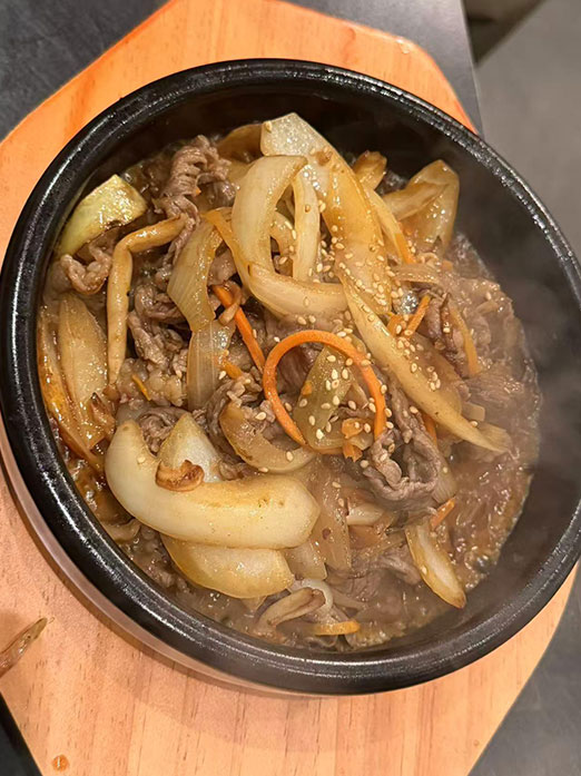 Simmered bulgogi beef with onions in a stone pot at Mr.Kimchi Korean Bistro, a Korean Restaurant in Oklahoma City