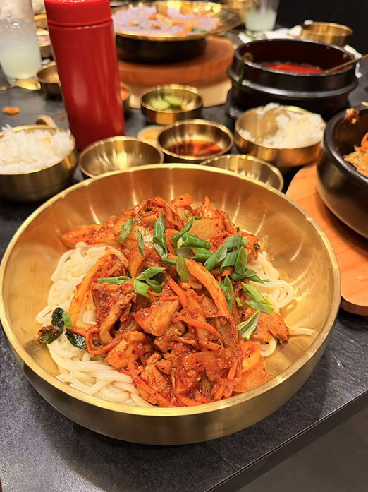 Spicy kimchi pork noodles in a golden bowl at Mr.Kimchi Korean Bistro, a Korean Restaurant in Oklahoma City