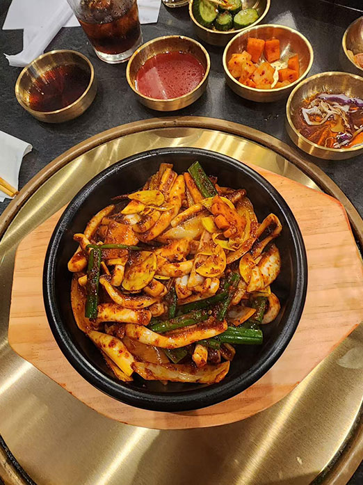 Spicy stir-fried squid with vegetables in a stone bowl on a hot plate at Mr.Kimchi Korean Bistro, a Korean Restaurant in Oklahoma City