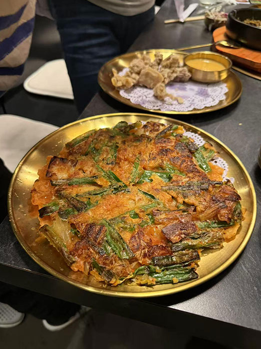 Crispy kimchi pancake with green onions served on a golden plate at Mr.Kimchi Korean Bistro, a Korean Restaurant in Oklahoma City