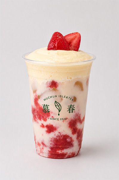 Strawberry cream milk tea with fruit puree layers, cream top and fresh strawberry garnish in branded cup at Muchun Isle & Tea, a Bubble Tea Shop in Bayside.