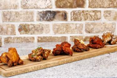 Assorted fried chicken wings served on a long wooden board