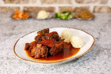 Braised meat with red sauce and rice balls, surrounded by side dishes