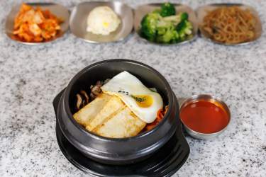 Dolsot stone bowl with rice, fried egg, vegetables, and red sauce