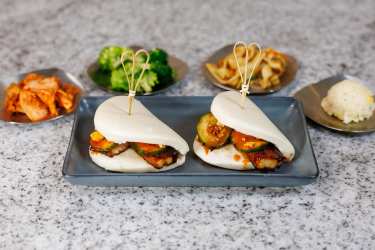 Two steamed buns filled with meat and vegetables on a plate