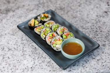 Vegetable gimbap rolls with avocado and dipping sauce on a plate