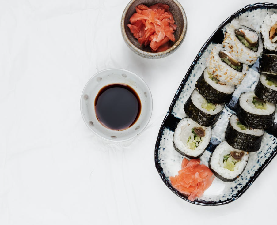 a plate of sushi with sauce and ginger