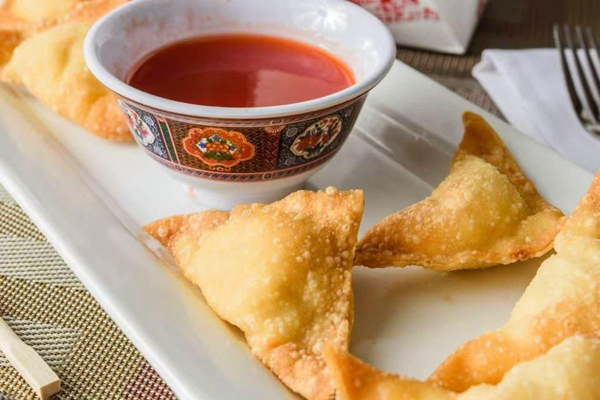 Crispy fried wontons served with a bowl of sweet and sour dipping sauce at New China Two，a Chinese Restaurant in Redding