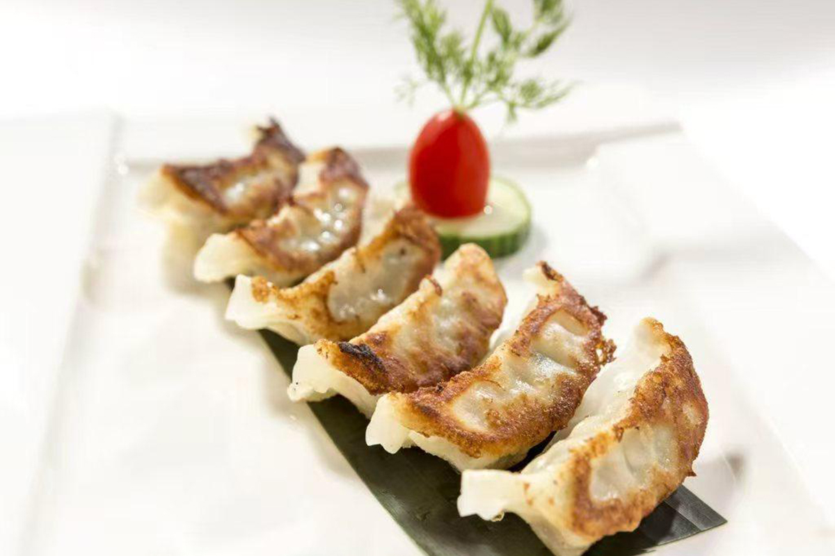 Pan-fried dumplings (gyoza) garnished with a cherry tomato, cucumber, and dill at New China Two，a Chinese Restaurant in Redding