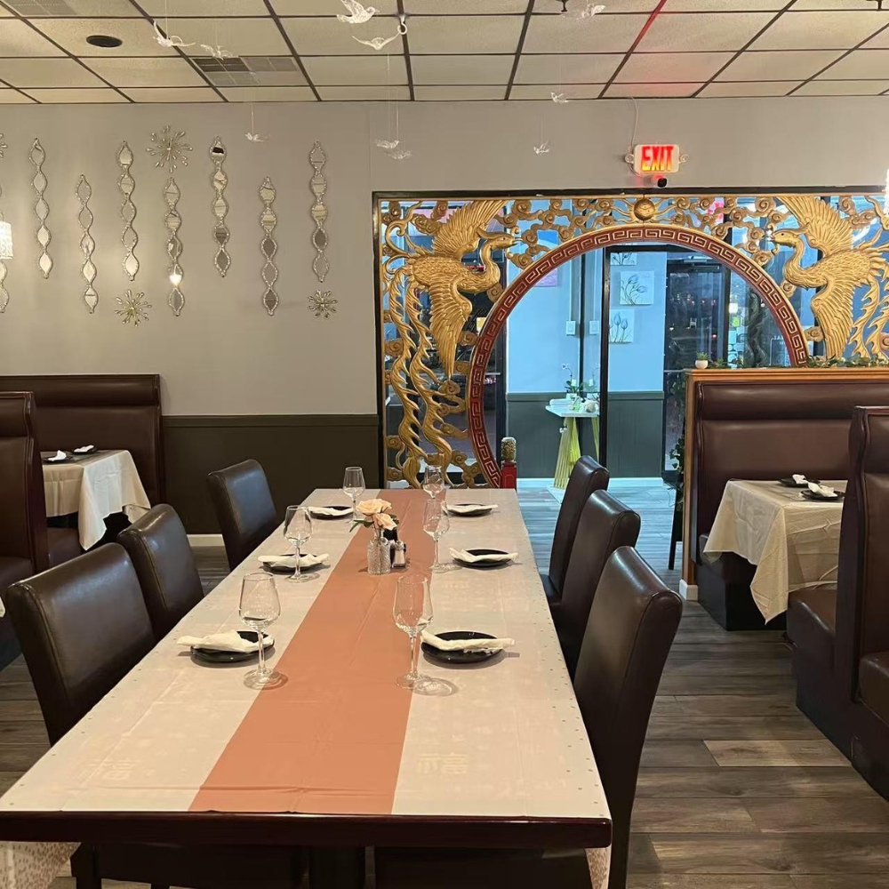 The dining area with a long table and golden decorative screen at New Imperial, a Chinese Restaurant in Easton.