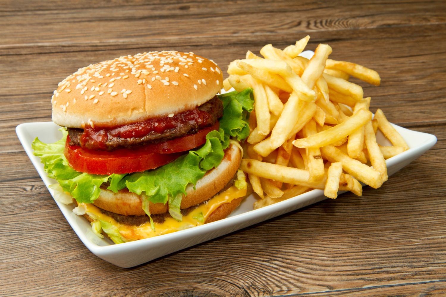 Double cheeseburger with lettuce, tomato, and fries on a white plate at NEW YORK BUFFALO WINGS, a American restaurant in Forest Park