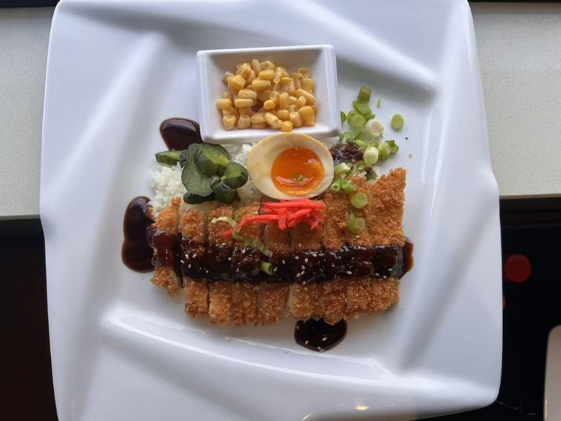 Rice bowl with crispy chicken katsu, egg, corn, and sauce at Ninja Ramen, a Japanese Restaurant in Englewood