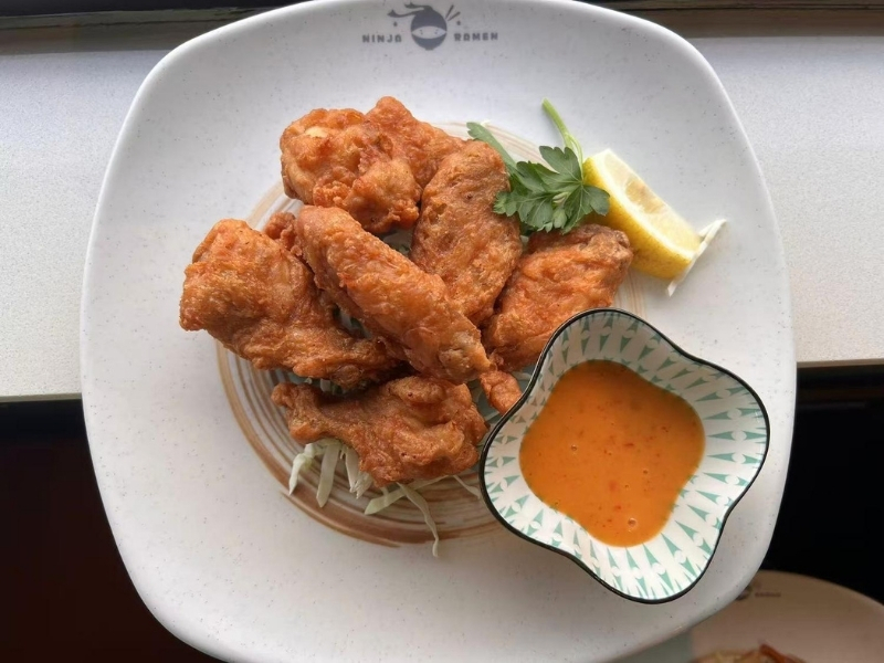 Crispy fried chicken wings with dipping sauce and lemon at Ninja Ramen, a Japanese Restaurant in Englewood