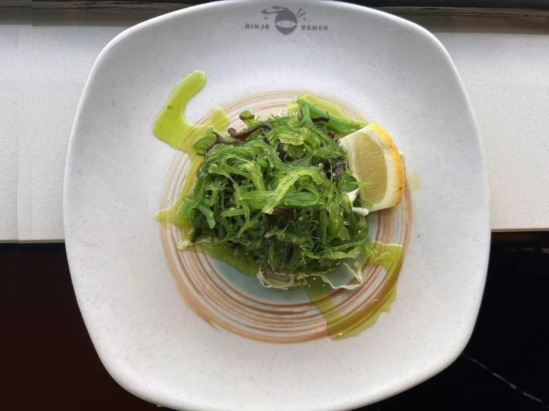 Fresh seaweed salad with lemon wedge, tossed in light dressing at Ninja Ramen, a Japanese Restaurant in Englewood