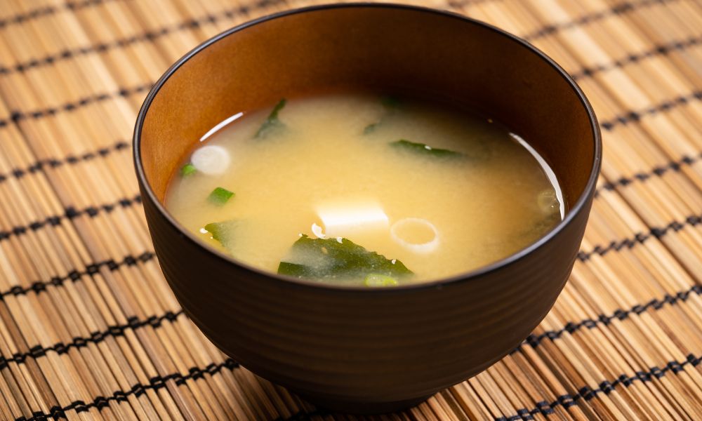 Warm miso soup with tofu, seaweed, and green onions in a brown bowl at Noodle House, a Japanese Sushi Restaurant in Flemington