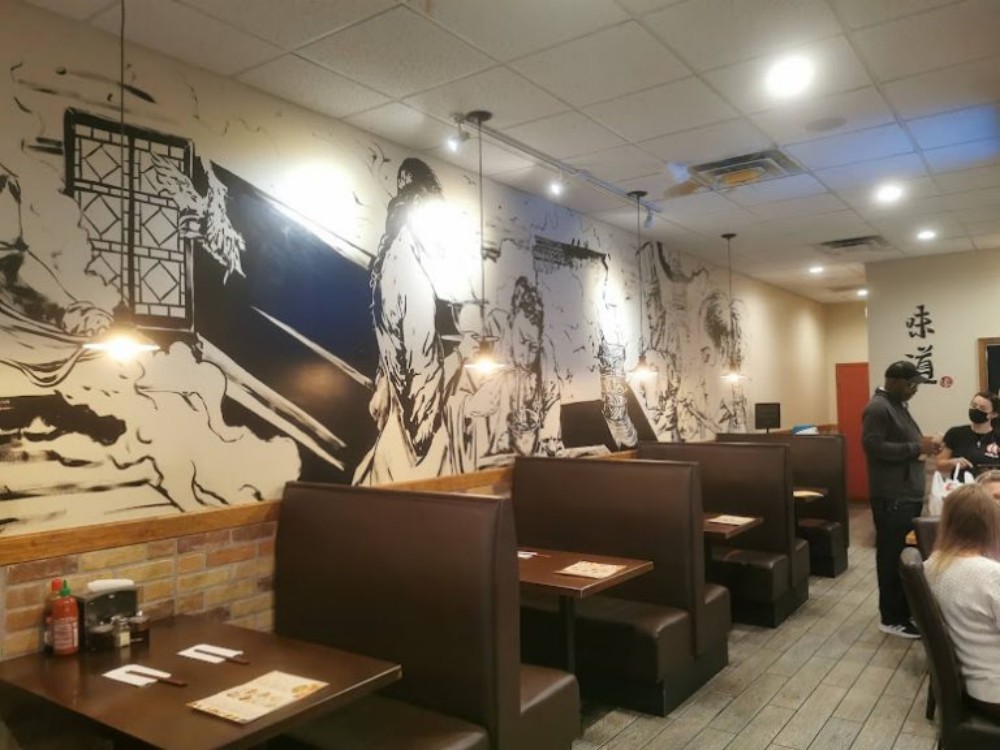 Booth seating with artistic black-and-white mural on the wall at Noodle Man , a Noodle shop in Virginia Beach