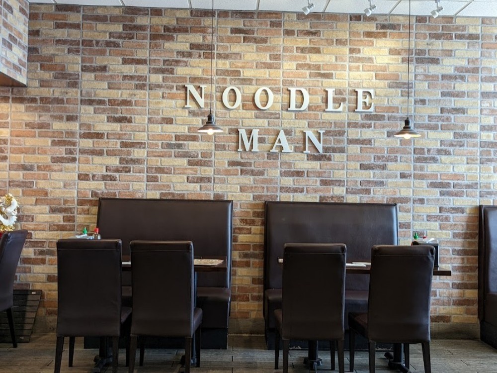 Close-up of NOODLE MAN letters on a rustic brick wall at Noodle Man , a Noodle shop in Virginia Beach
