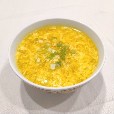 Egg drop soup garnished with chopped green scallions.