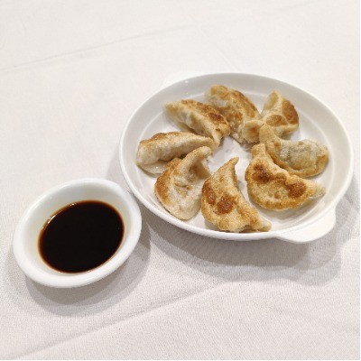 Pan‑fried dumplings with side bowl of soy sauce.