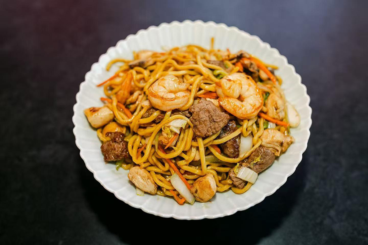 Stir-fried soba noodles with chicken, beef, shrimp, bok choy, shredded carrots, and mushrooms in savory house sauce at Oishii Express, a Japanese Restaurant in Oklahoma City