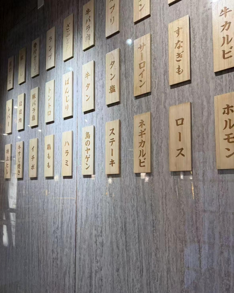Authentic wooden Japanese menu plaques on a textured wall at Oishii Sushi House, a Japanese Restaurant in Dacula.