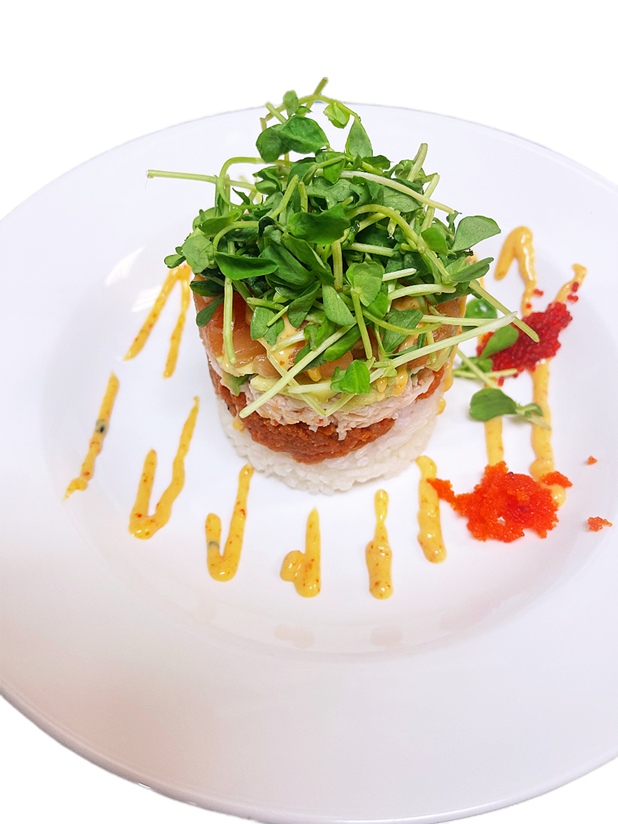 Layered sushi stack topped with fresh greens at O-Ku Sushi & Poke, a Japanese Restaurant in Sandy