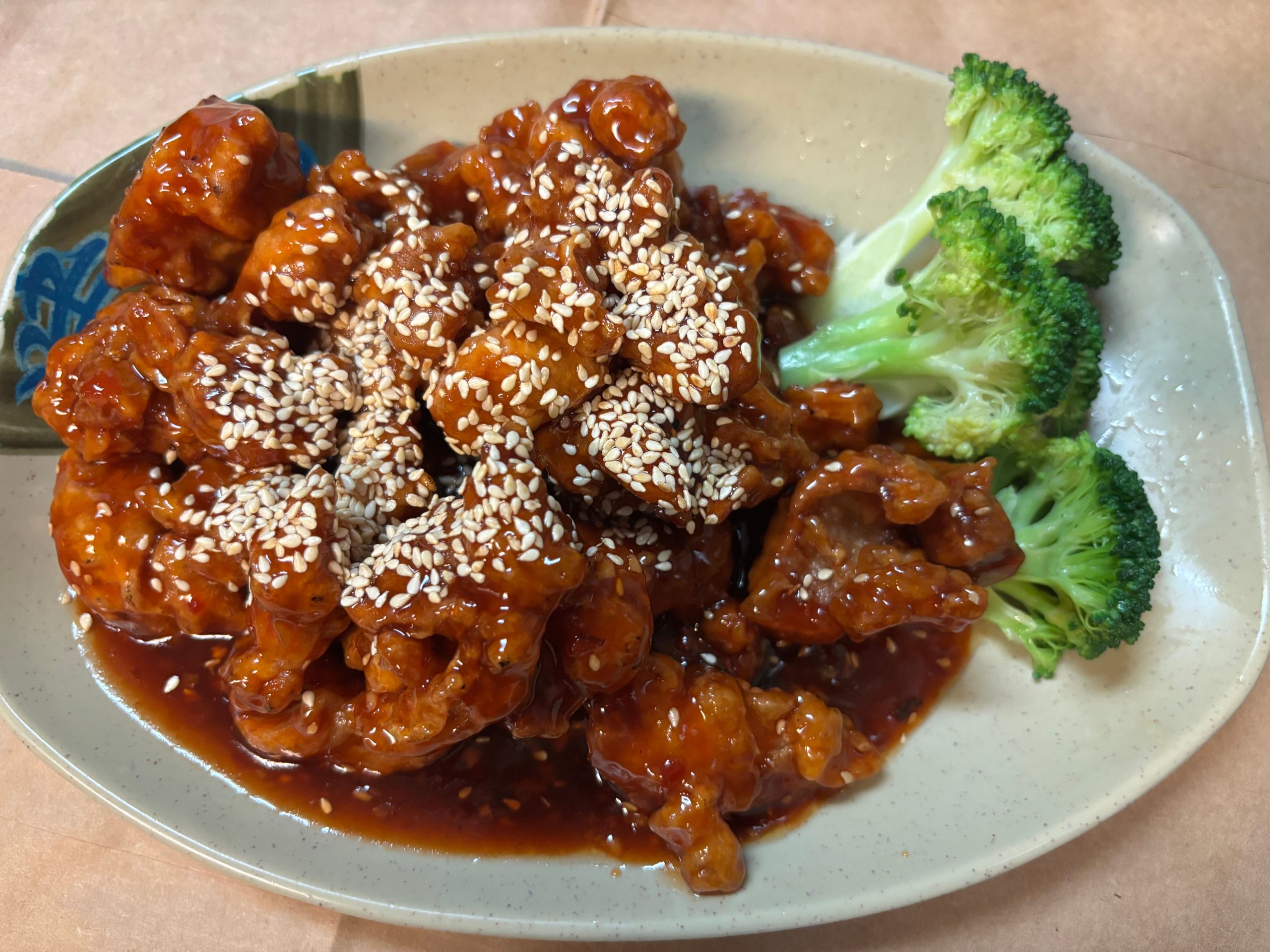 Sesame glazed sweet chicken served with fresh broccoli florets at The Wok, an Asian Fusion Restaurant in Rochester