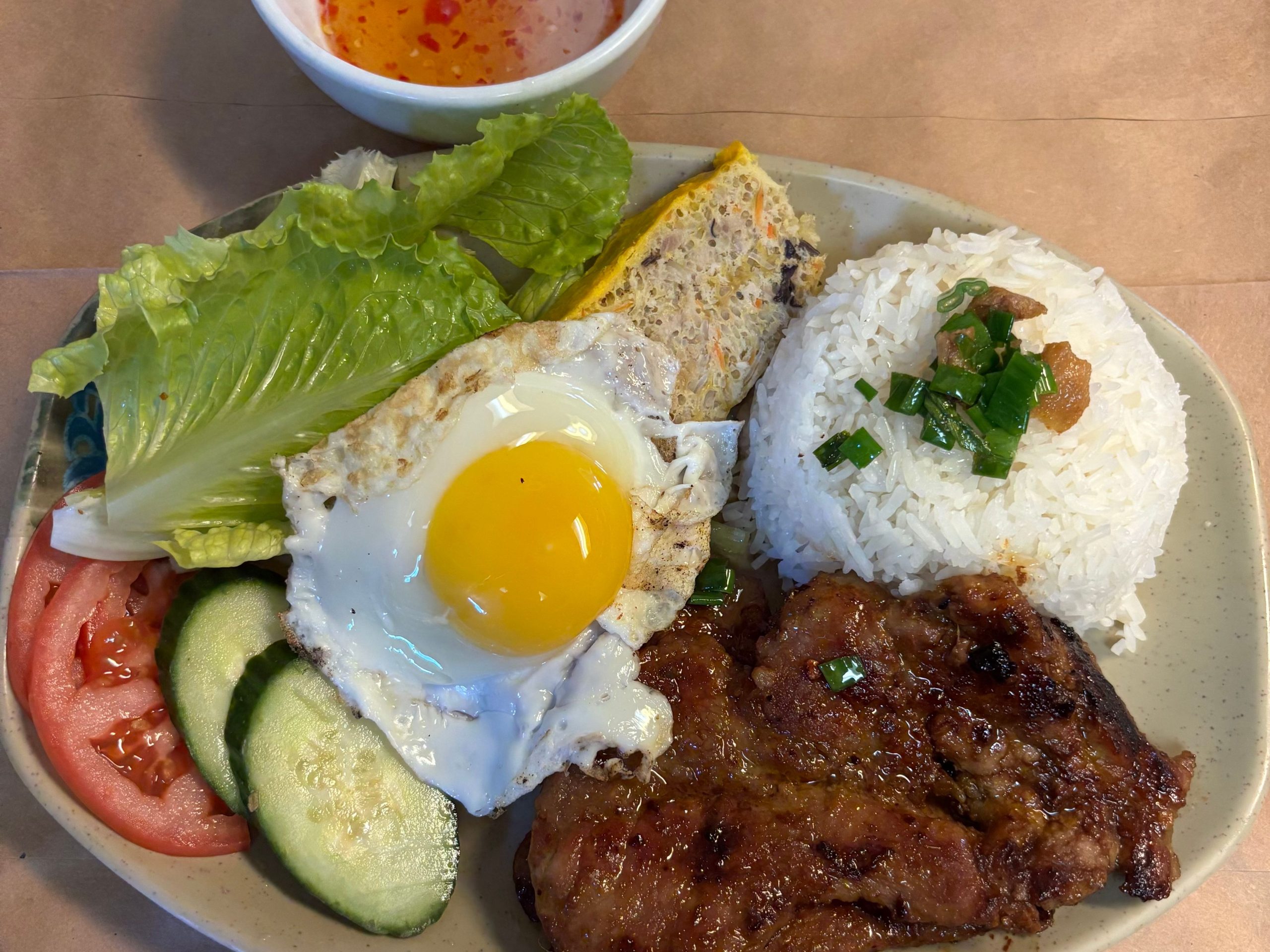 Grilled pork chop rice platter with fried egg, fresh vegetables and herbs at The Wok, an Asian Fusion Restaurant in Rochester