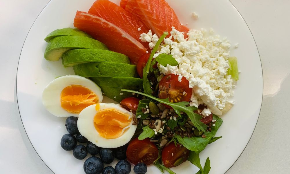 White plate with fresh raw salmon, avocado, soft-boiled eggs, cottage cheese, blueberries and mixed leafy greens at Zen Bowl, a Healthy Poke Restaurant in Imperial
