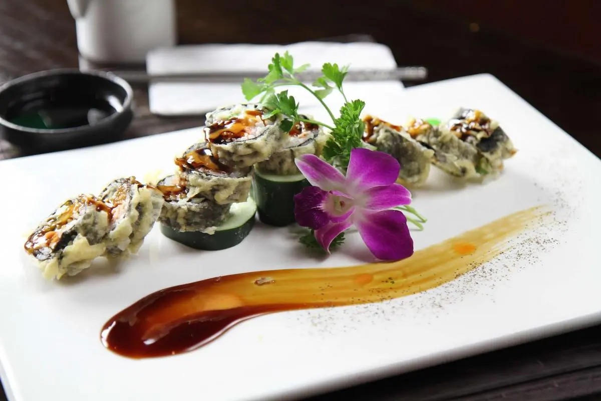 Tempura sushi roll with drizzled sauce, garnished with orchid, at Oriental Palace, a Asian Restaurant in Lawnside