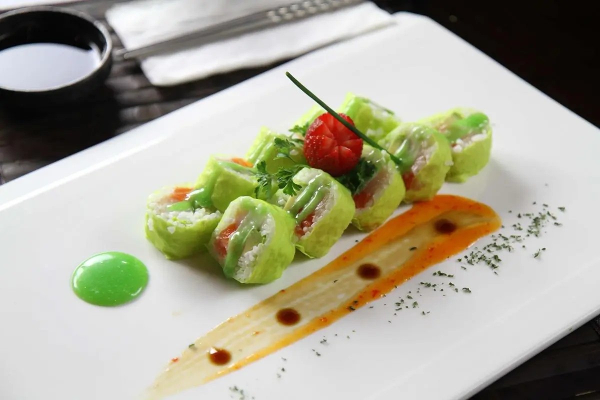 Green sushi roll with strawberry garnish and colorful sauce, at Oriental Palace, a Asian Restaurant in Lawnside