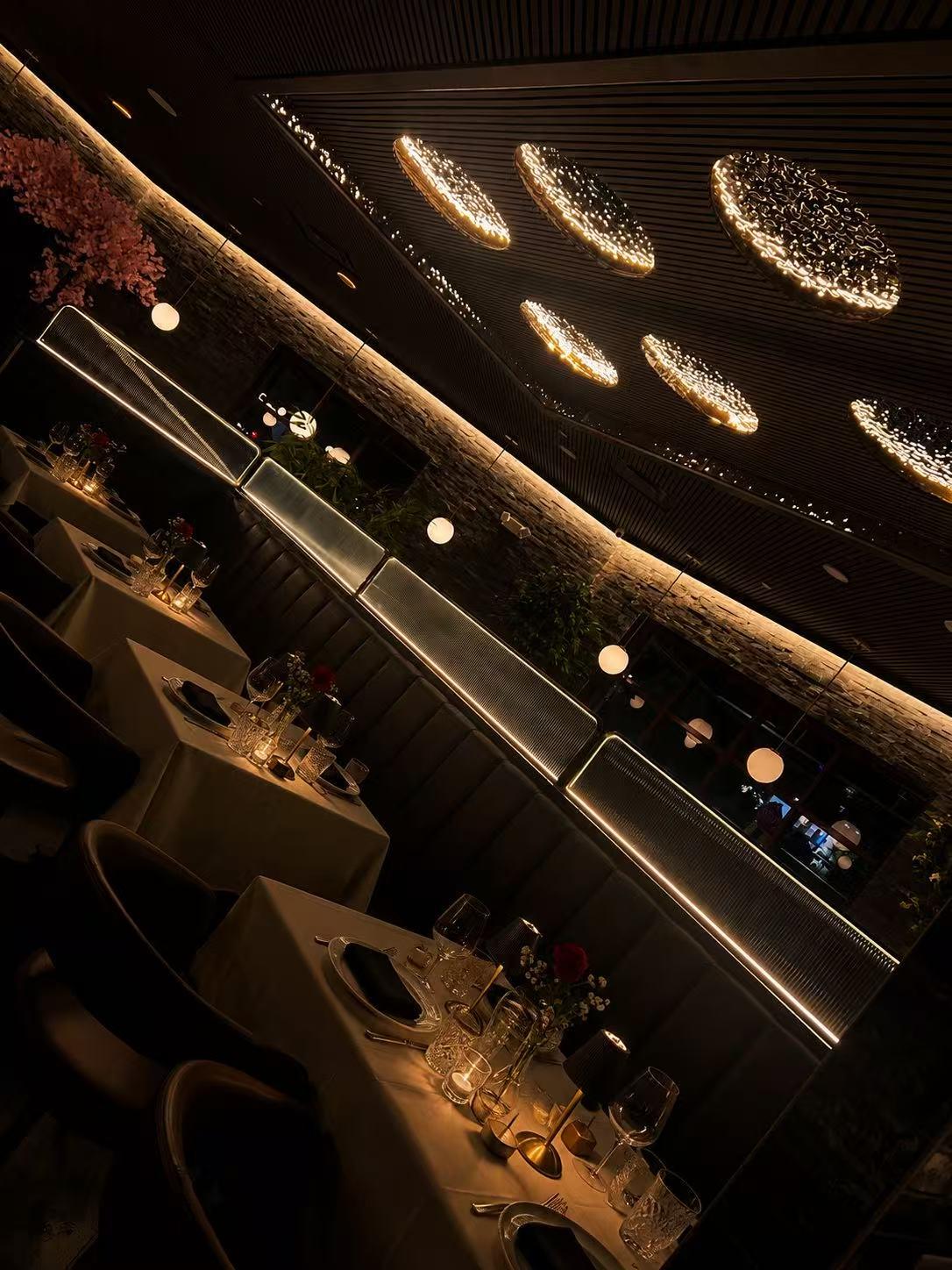 Elegant dim dining room with set tables, leather booths and glowing oval ceiling lights at Origami Asian Fusion Exton, an Asian Fusion Restaurant in Exton